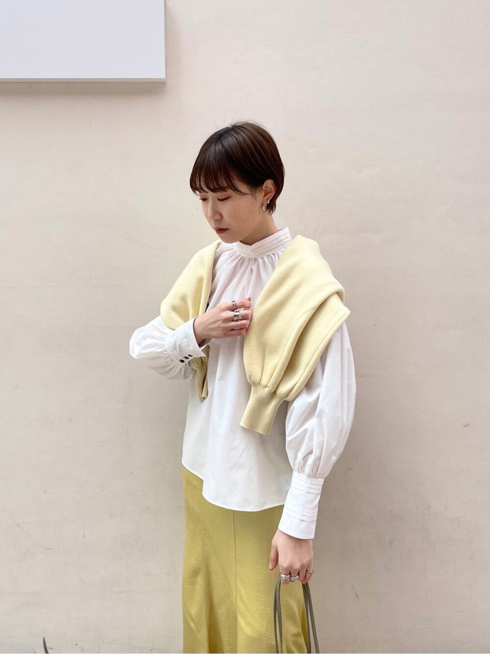 ホワイト系のシャツ/ブラウス、イエロー系のスカート、ベージュ系のハンドバッグを着用したレディースの冬コーディネートの6枚目の写真