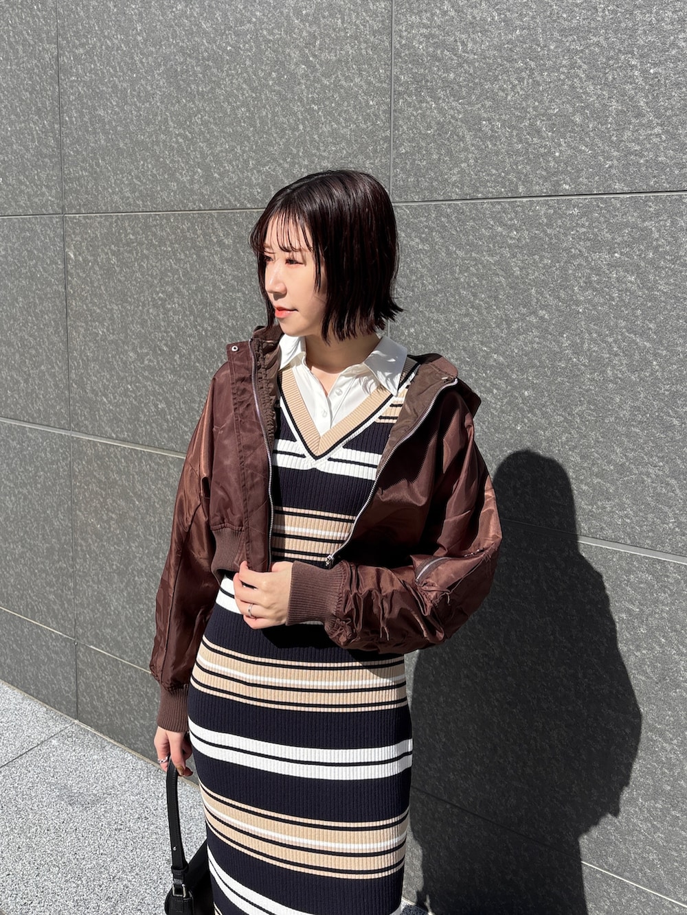 ベージュ系のワンピース、ブラック系のハンドバッグ、ブラウン系のブルゾンを着用したレディースの春コーディネートの5枚目の写真