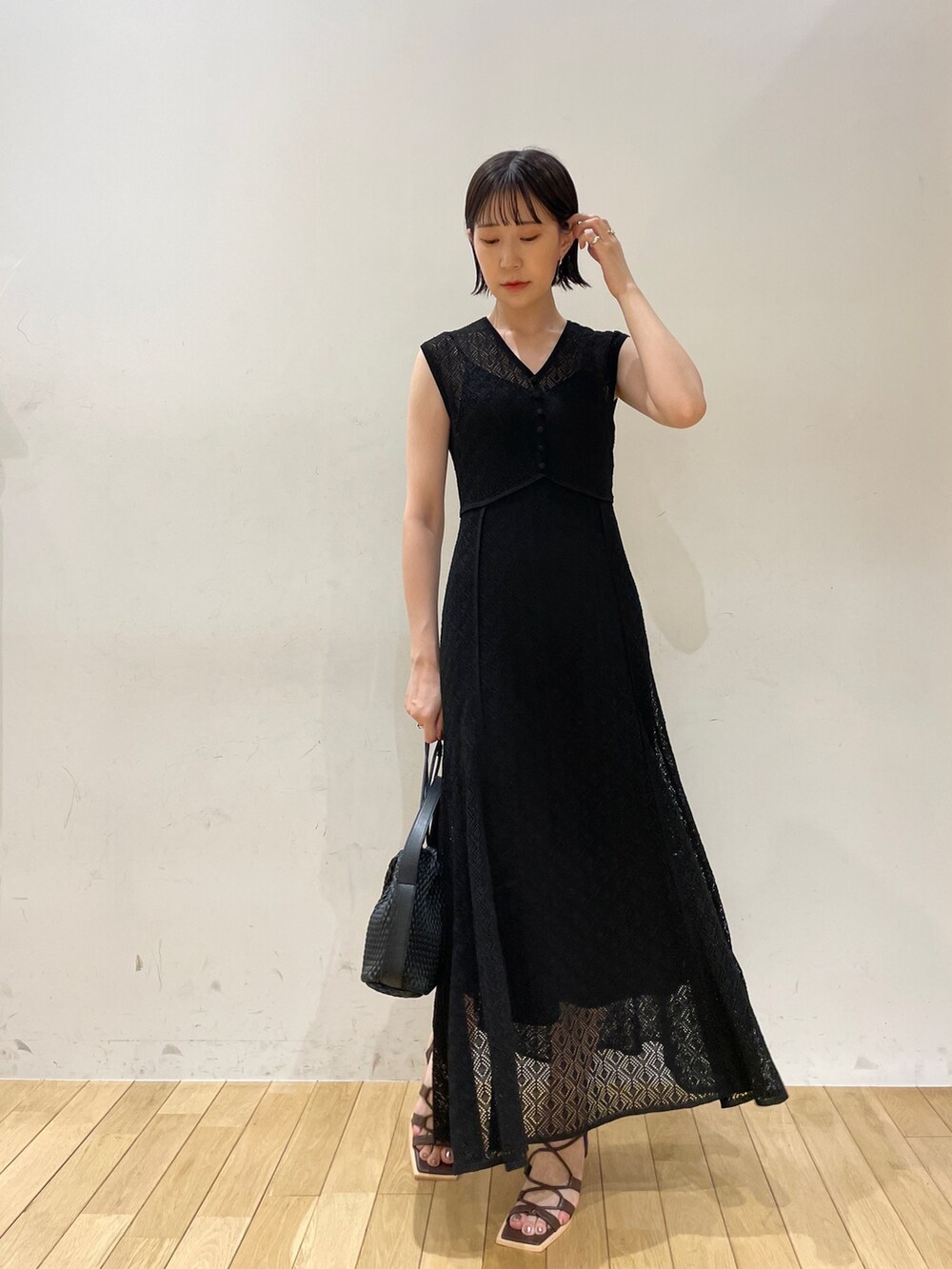 ブラック系のワンピース、ブラック系のハンドバッグ、ブラウン系のサンダルを着用したレディースの夏コーディネートの4枚目の写真