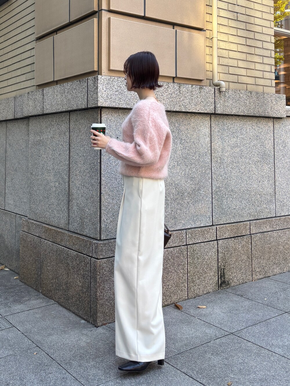 ピンク系のニット/セーター、ブラウン系のハンドバッグ、ホワイト系のその他パンツを着用したレディースの秋コーディネートの2枚目の写真