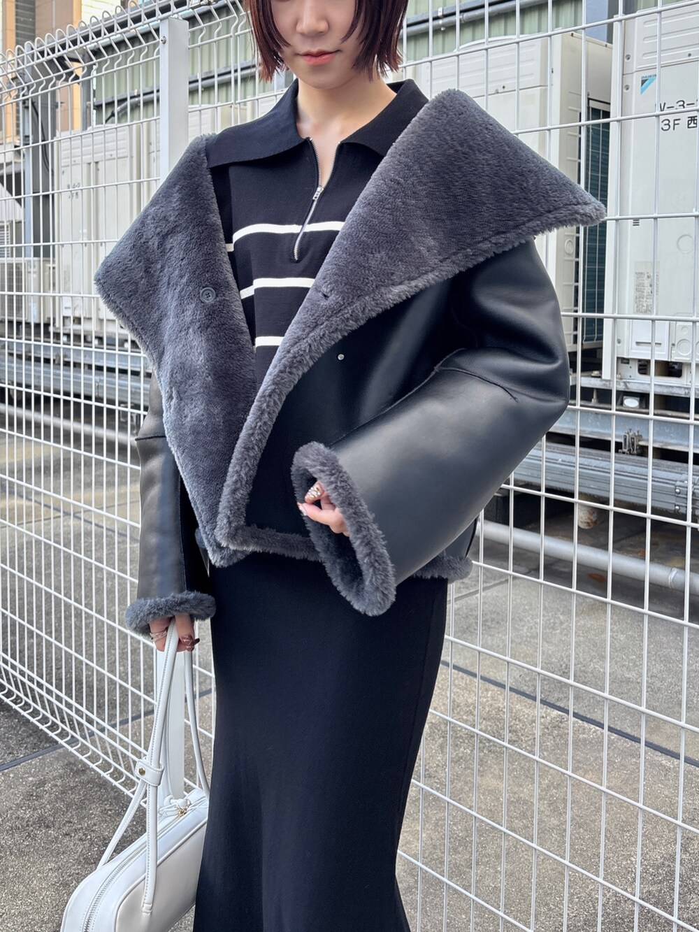 ブラック系のニット/セーター、ブラック系のスカート、グレー系のムートンコートを着用したレディースの冬コーディネートの7枚目の写真