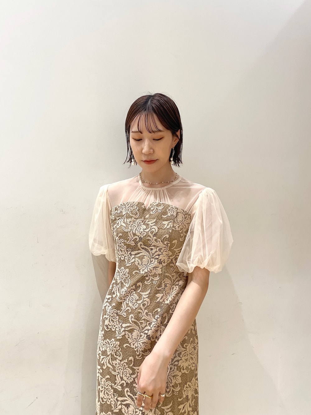 ベージュ系のハンドバッグ、ベージュ系のパンプス、ベージュ系のドレスを着用したレディースの秋コーディネートの8枚目の写真