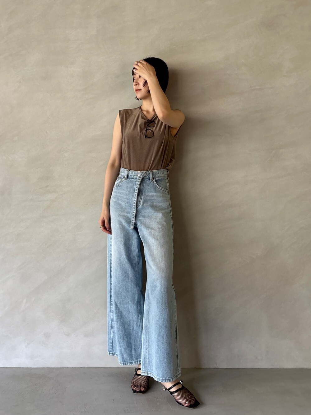 ブルー系のデニムパンツ、ブラック系のサンダル、ブラウン系のTシャツ/カットソーを着用したレディースの夏コーディネートの2枚目の写真