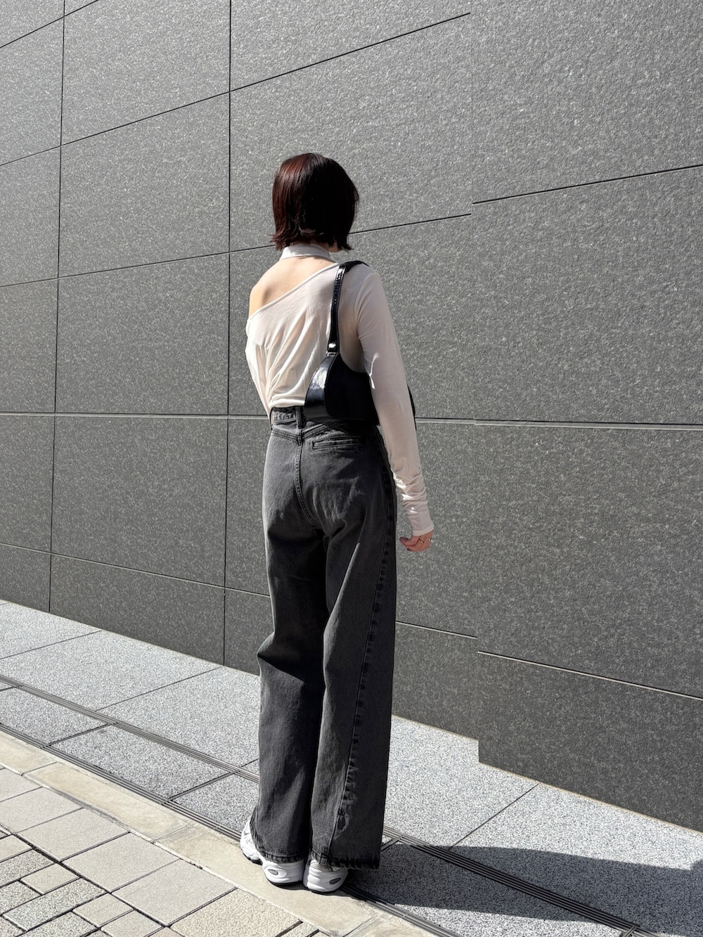ブラック系のデニムパンツ、ホワイト系のTシャツ/カットソー、ブラック系のハンドバッグを着用したレディースの春コーディネートの4枚目の写真