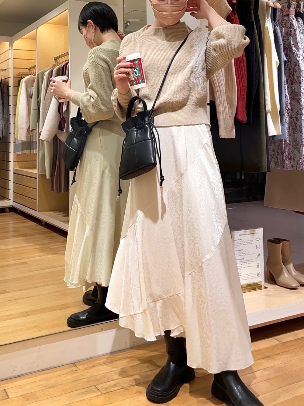 ベージュ系のニット/セーター、ホワイト系のスカート、ブラック系のハンドバッグを着用したレディースの冬コーディネートの3枚目の写真