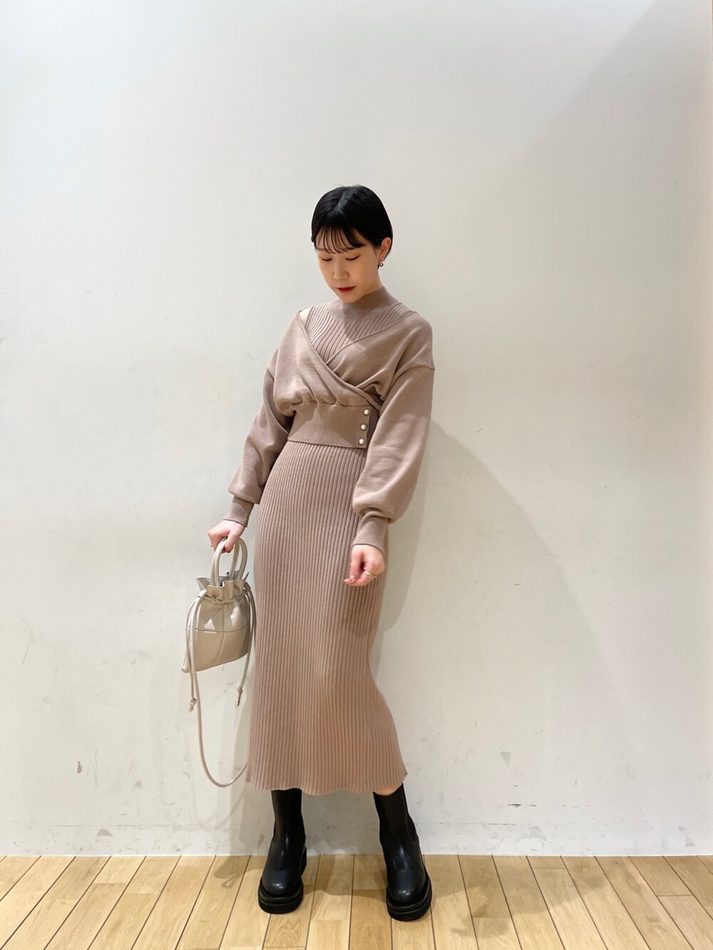 ベージュ系のワンピース、ホワイト系のハンドバッグ、ブラック系のブーツを着用したレディースの冬コーディネートの2枚目の写真