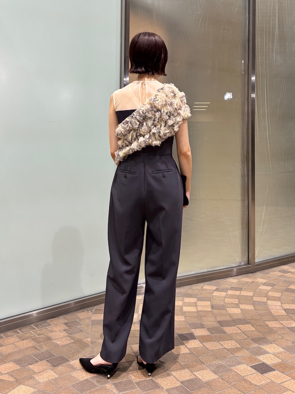 グレー系のパンツドレス、ブラック系のクラッチバッグ、ブラック系のパンプスを着用したレディースの夏コーディネートの5枚目の写真