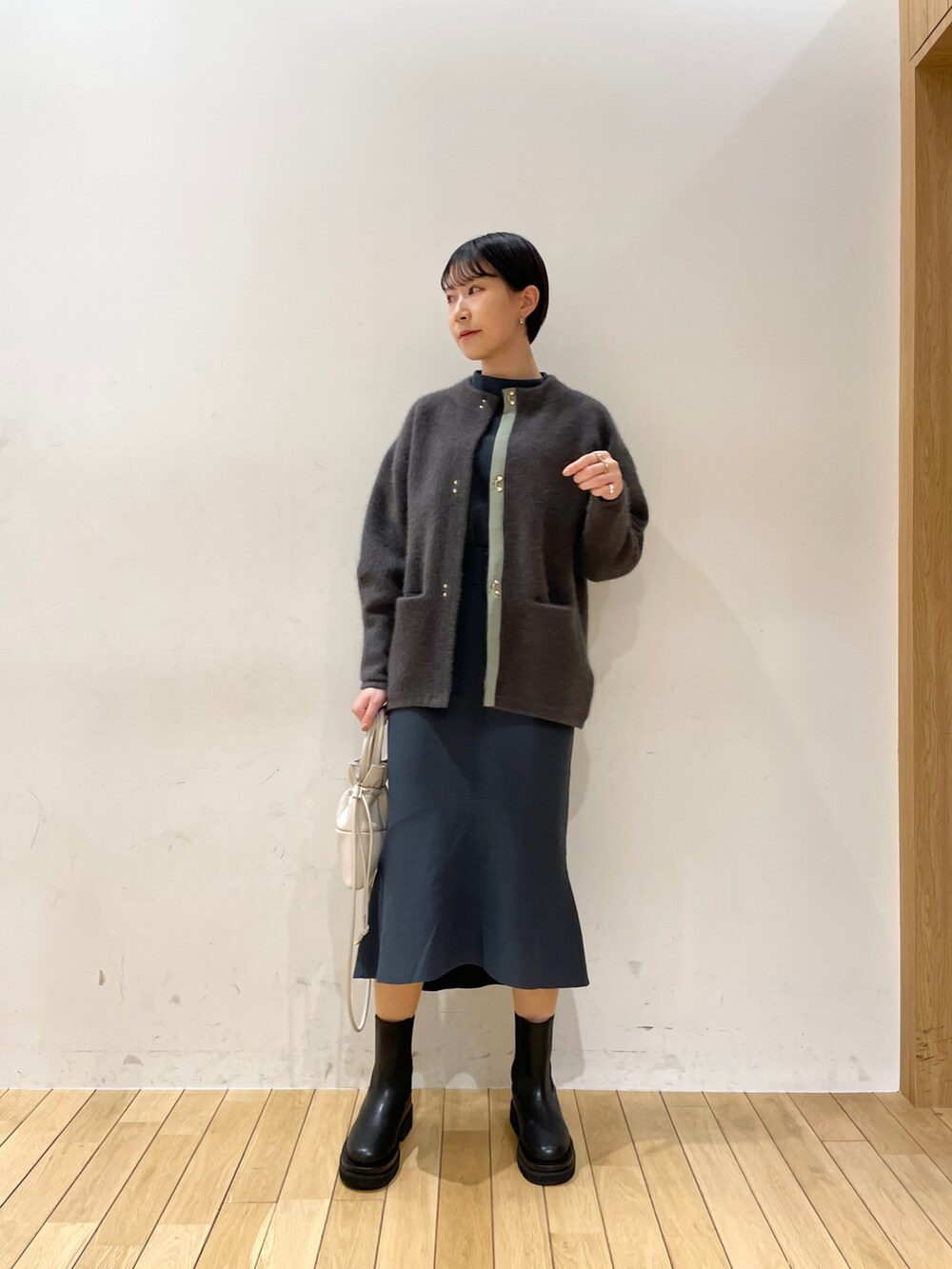 グレー系のカーディガン/ボレロ、グリーン系のニット/セーター、グリーン系のスカートを着用したレディースの冬コーディネートの2枚目の写真