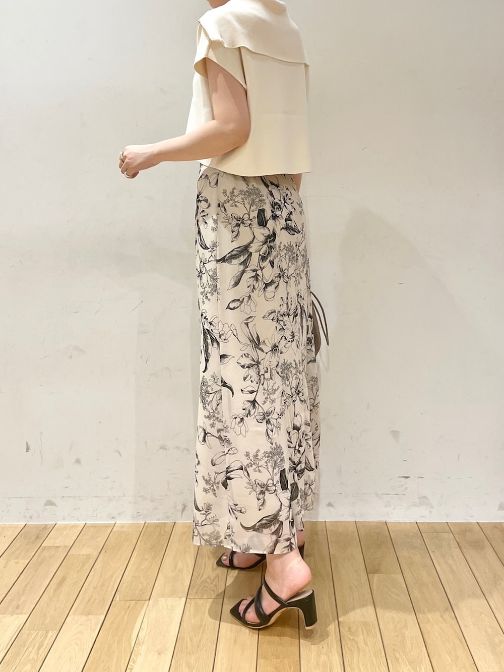 ホワイト系のニット/セーター、ホワイト系のスカート、ブラウン系のハンドバッグを着用したレディースの春コーディネートの4枚目の写真