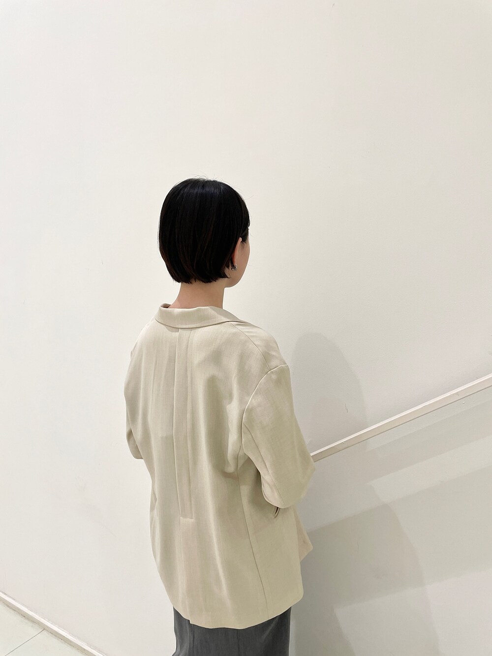 ベージュ系のテーラードジャケット、グレー系のワンピース、ブラック系のサンダルを着用したレディースの春コーディネートの7枚目の写真