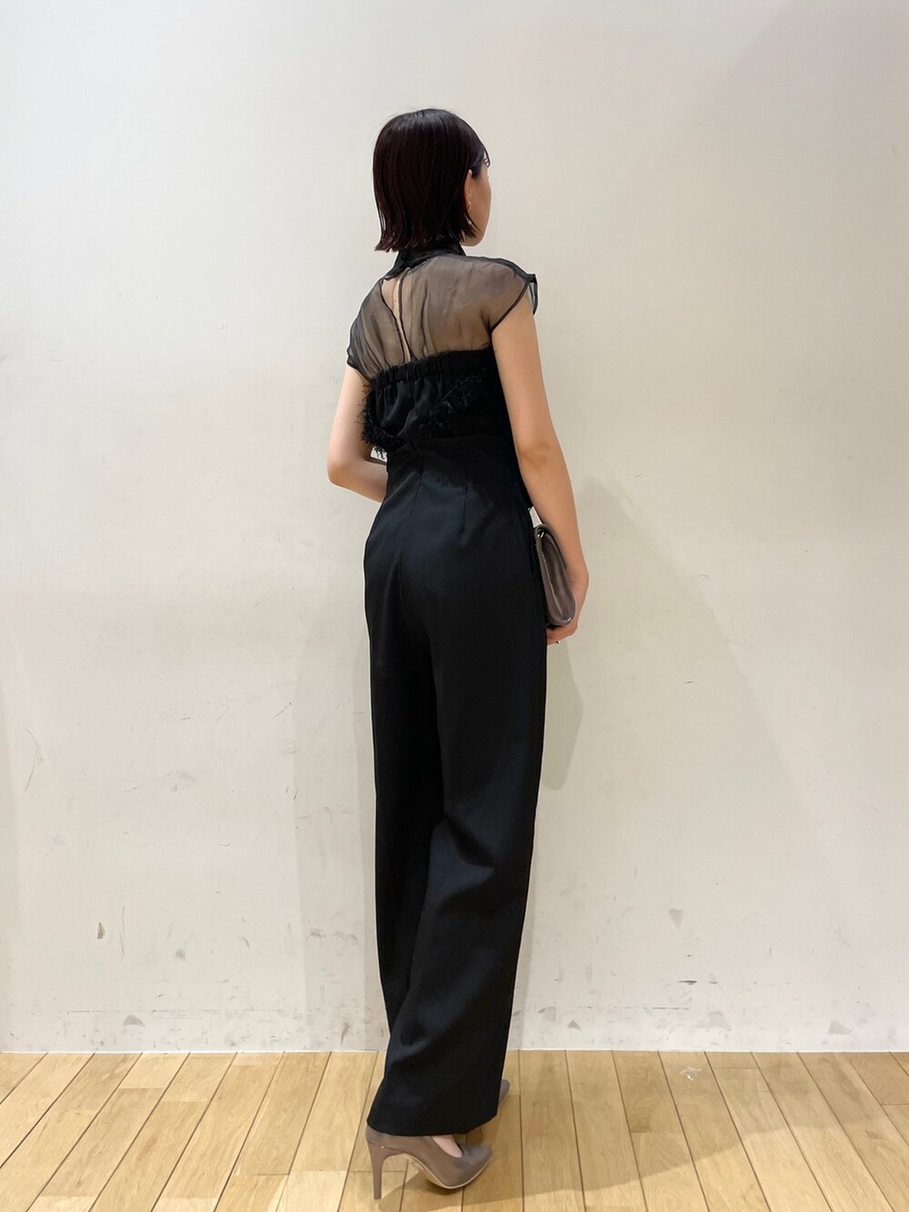 シルバー系のハンドバッグ、ブラック系のパンツドレス、シルバー系のパンプスを着用したレディースの秋コーディネートの3枚目の写真