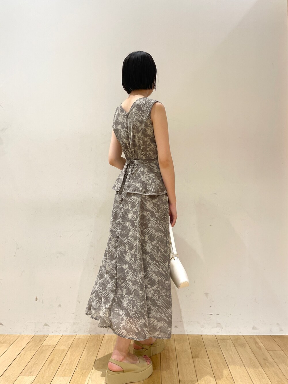 グレー系のワンピース、ホワイト系のハンドバッグ、ベージュ系のサンダルを着用したレディースの夏コーディネートの5枚目の写真