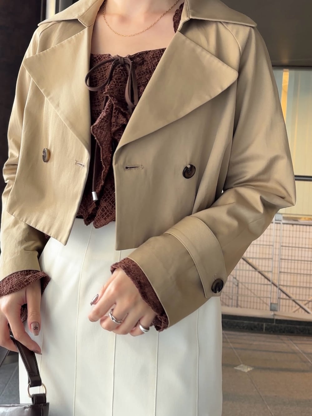 ブラウン系のシャツ/ブラウス、ベージュ系のトレンチコート、ブラウン系のハンドバッグを着用したレディースの冬コーディネートの2枚目の写真