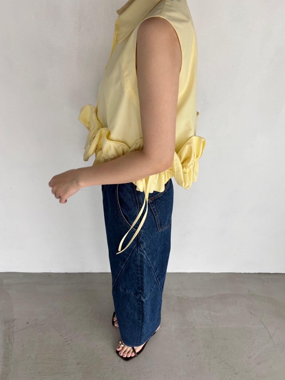 ブルー系のデニムパンツ、イエロー系のシャツ/ブラウス、シルバー系のハンドバッグを着用したレディースの夏コーディネートの6枚目の写真