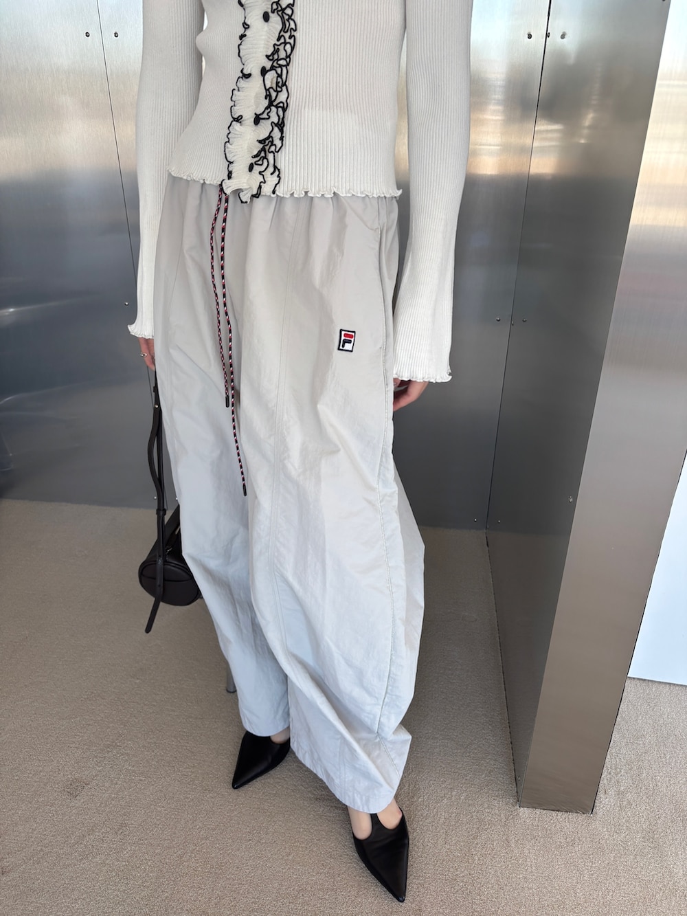 ベージュ系のその他パンツ、ホワイト系のニット/セーター、ブラック系のパンプスを着用したレディースの春コーディネートの3枚目の写真