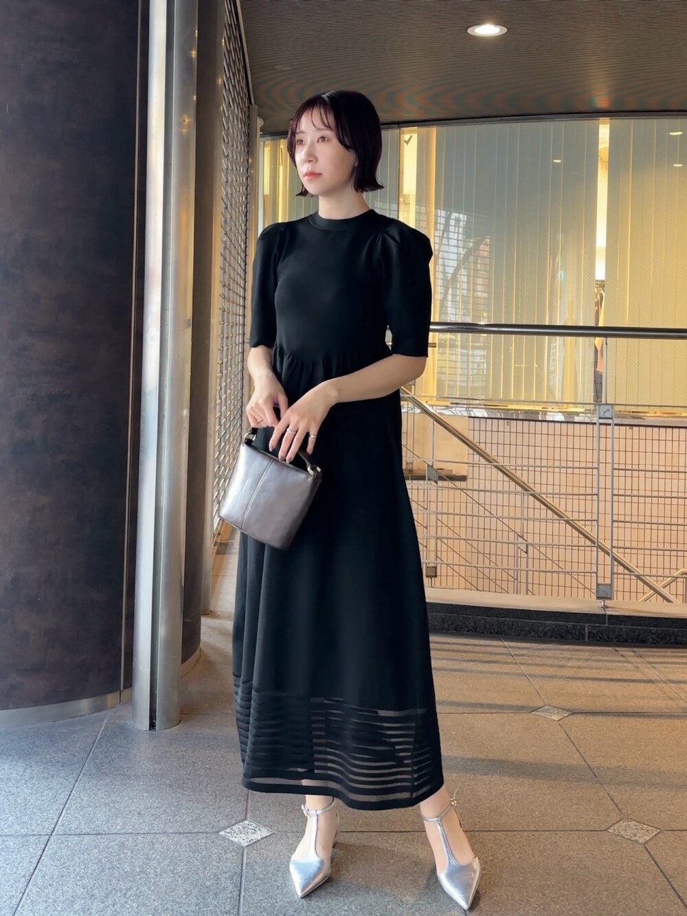 ブラウン系のハンドバッグ、シルバー系のパンプス、ブラック系のワンピースを着用したレディースの冬コーディネートの2枚目の写真