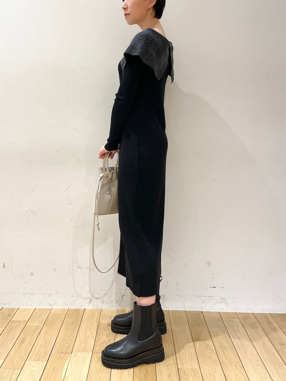 ブラック系のワンピース、ホワイト系のハンドバッグ、ブラック系のブーツを着用したレディースの冬コーディネートの3枚目の写真