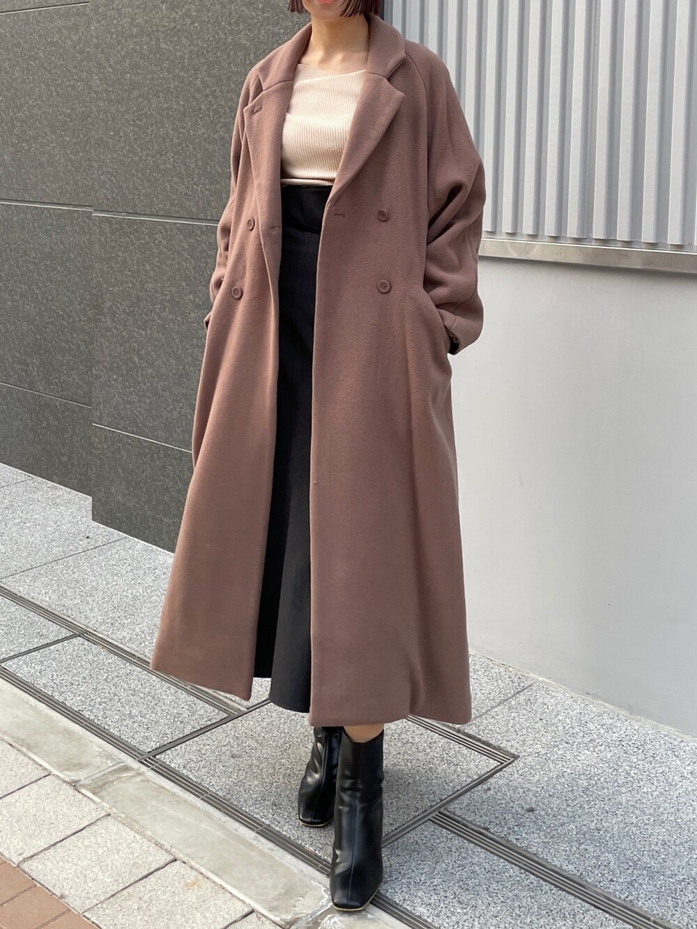 ホワイト系のニット/セーター、ブラウン系のチェスターコート、グレー系のスカートを着用したレディースの冬コーディネートの7枚目の写真