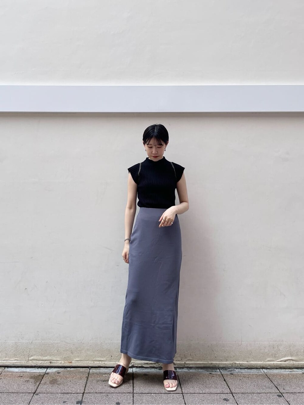 ホワイト系のサンダル、ブルー系のスカート、ブラック系のニット/セーターを着用したレディースの夏コーディネートの3枚目の写真