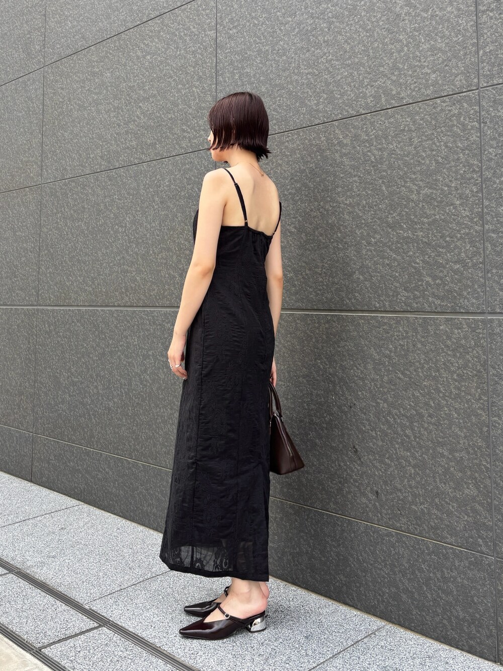ブラック系のワンピース、ブラウン系のパンプス、ブラウン系のボストンバッグを着用したレディースの夏コーディネートの3枚目の写真