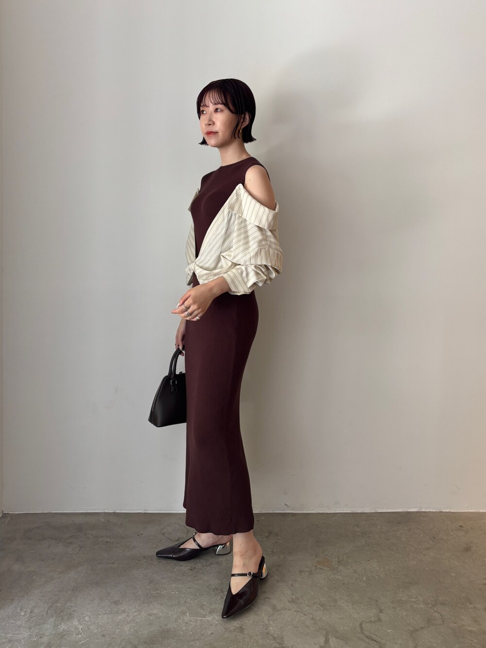 ブラウン系のワンピース、ブラウン系のボストンバッグ、ブラウン系のパンプスを着用したレディースの秋コーディネートの3枚目の写真