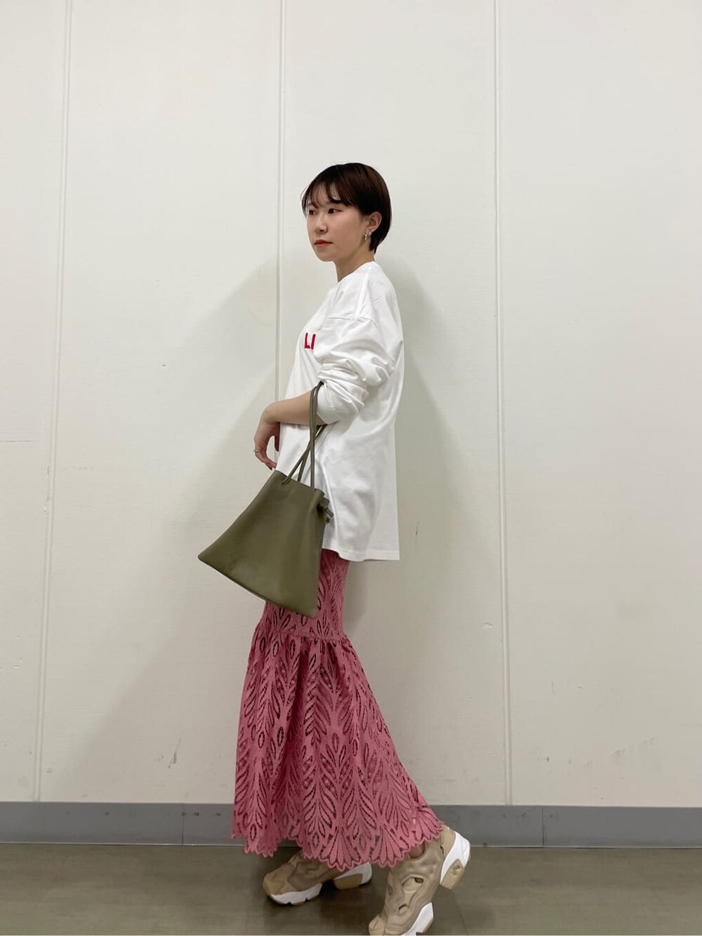 ピンク系のスカート、ホワイト系のTシャツ/カットソー、ベージュ系のスニーカーを着用したレディースの春コーディネートの2枚目の写真