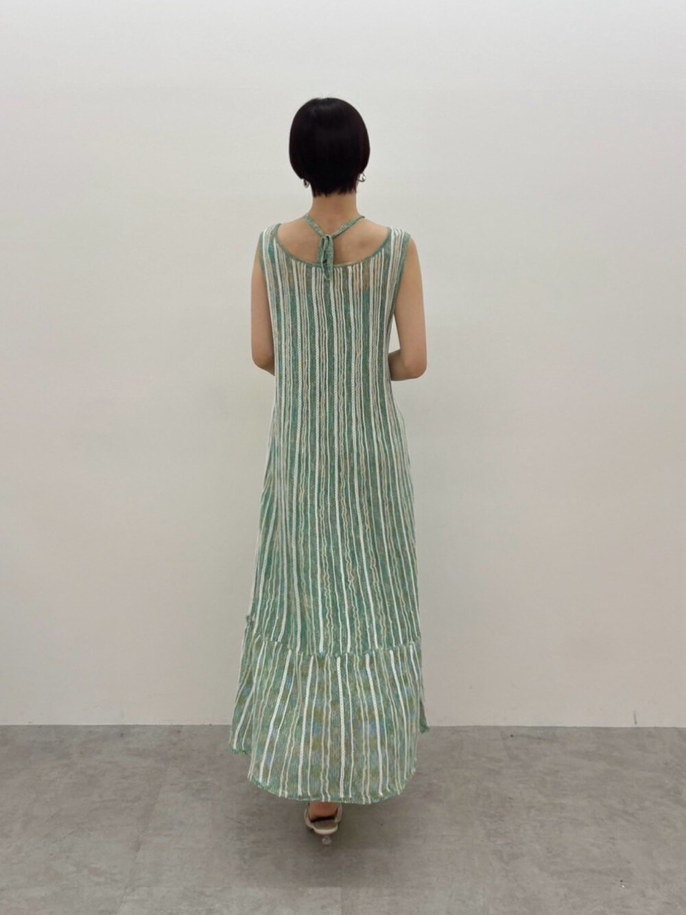 グリーン系のワンピース、ホワイト系のサンダル、シルバー系のピアス（両耳用）を着用したレディースの春コーディネートの7枚目の写真