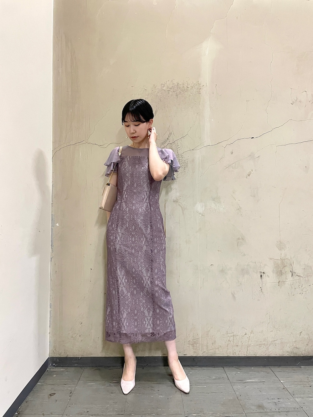 パープル系のドレス、ベージュ系のクラッチバッグ、ベージュ系のパンプスを着用したレディースの秋コーディネートの2枚目の写真
