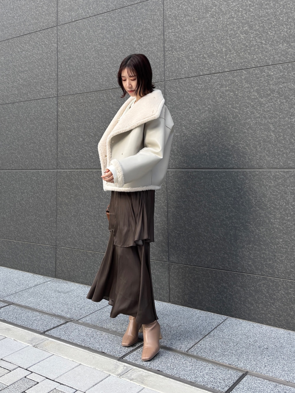 ホワイト系のムートンコート、ホワイト系のアンサンブル、イエロー系のハンドバッグを着用したレディースの冬コーディネートの3枚目の写真