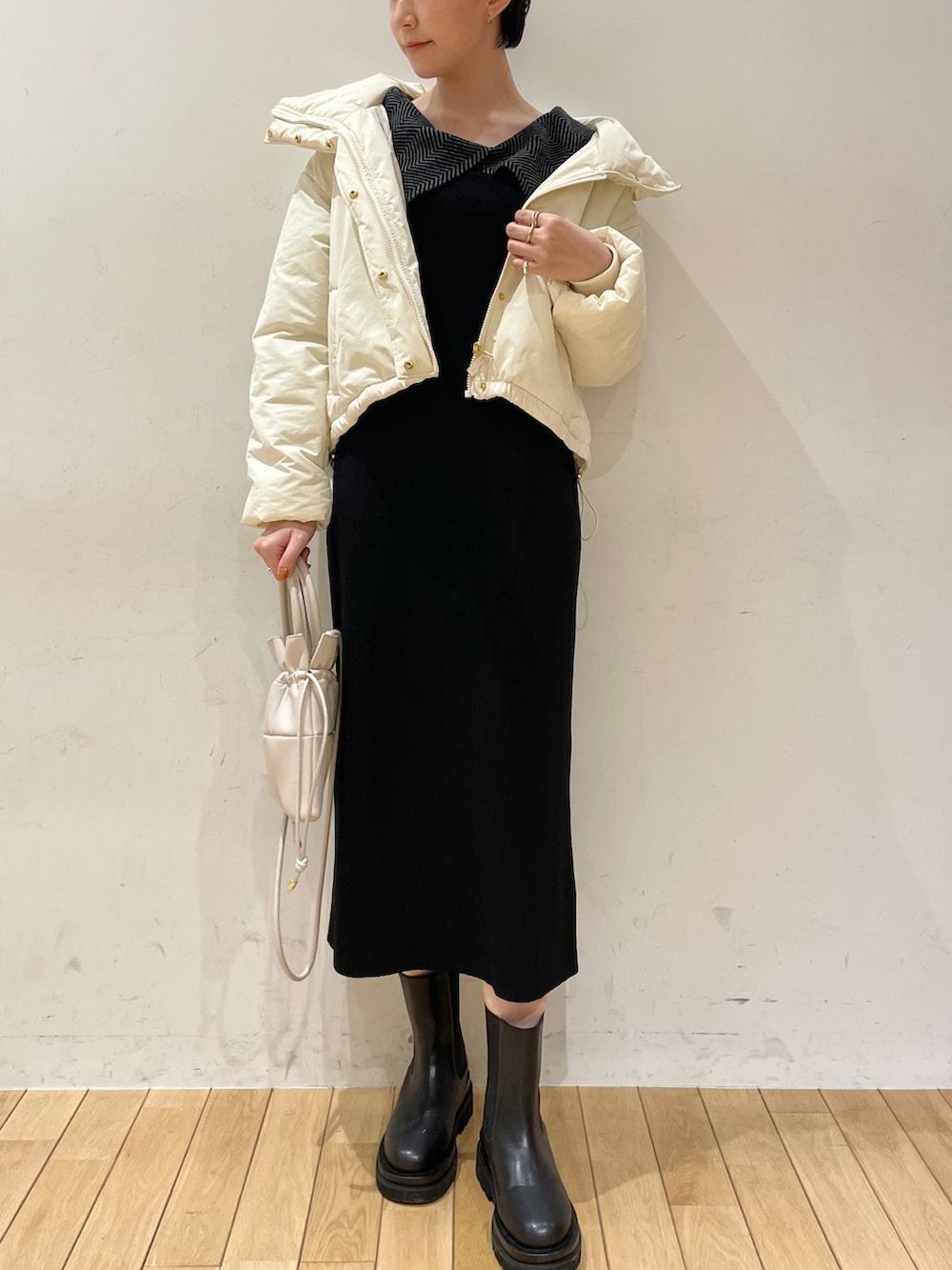ブラック系のワンピース、ホワイト系のハンドバッグ、ブラック系のブーツを着用したレディースの冬コーディネートの5枚目の写真