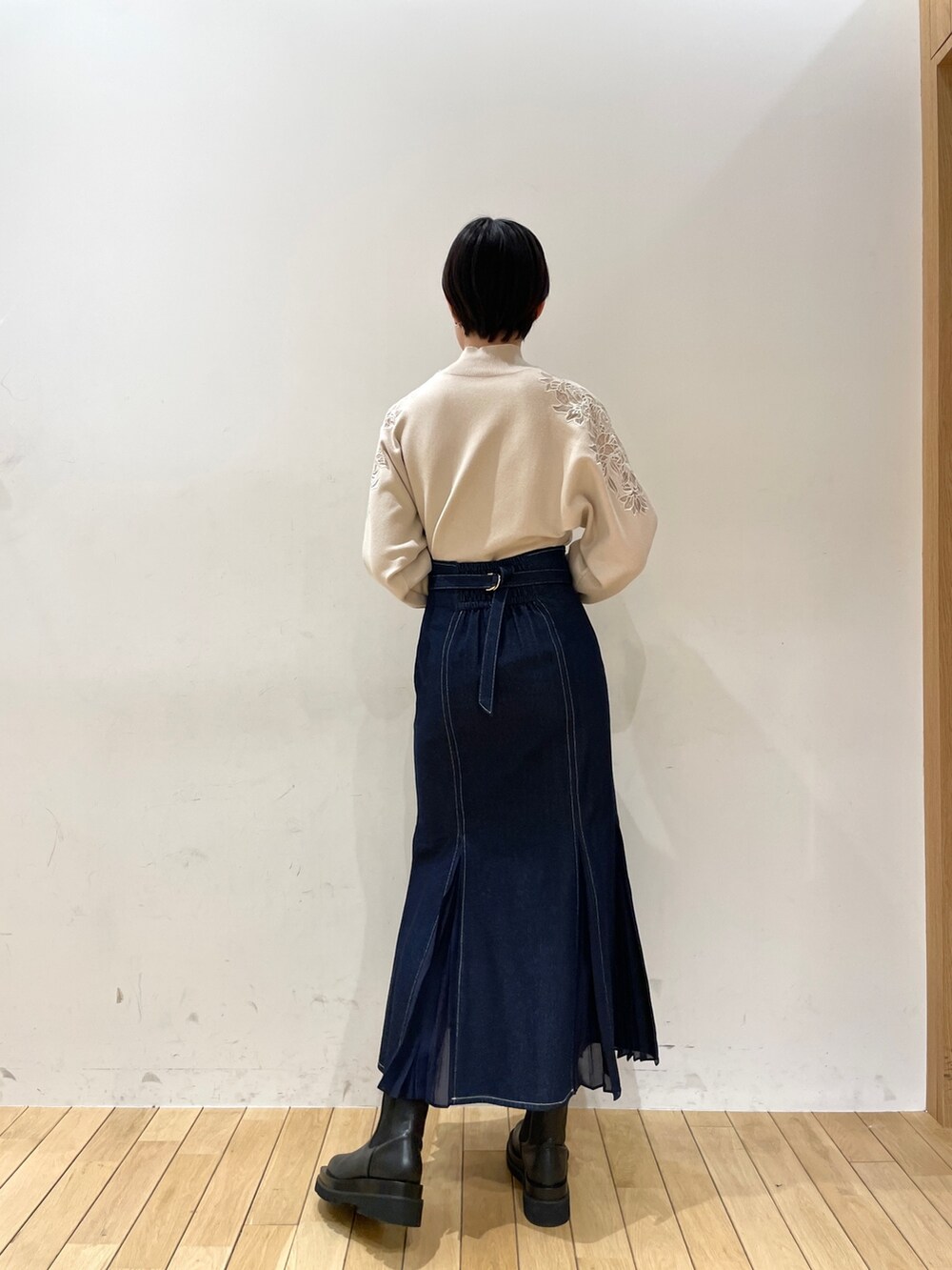 ホワイト系のニット/セーター、ブルー系のスカート、ブラック系のブーツを着用したレディースの冬コーディネートの4枚目の写真