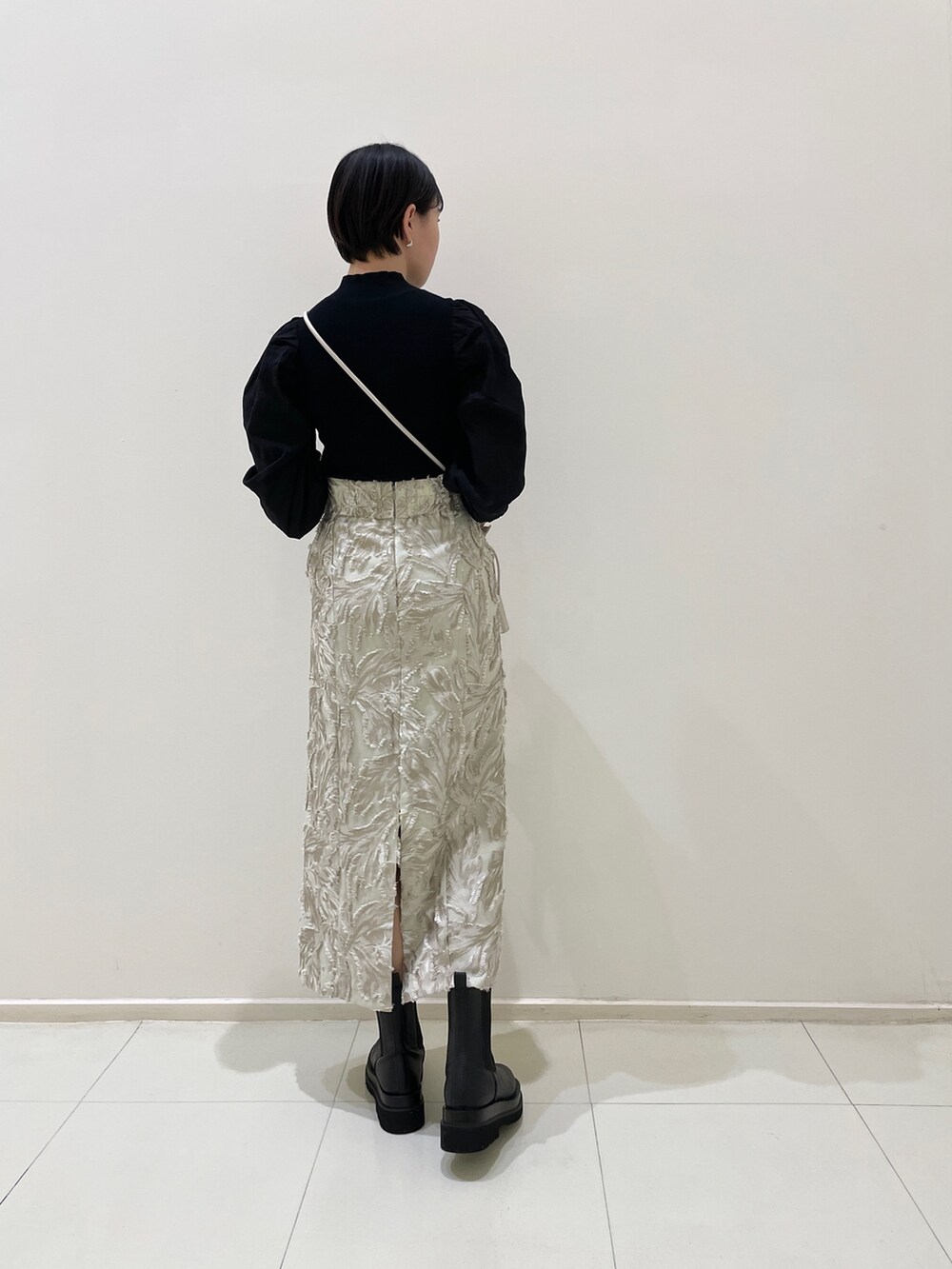 ブラック系のニット/セーター、ベージュ系のスカート、ホワイト系のハンドバッグを着用したレディースの冬コーディネートの4枚目の写真