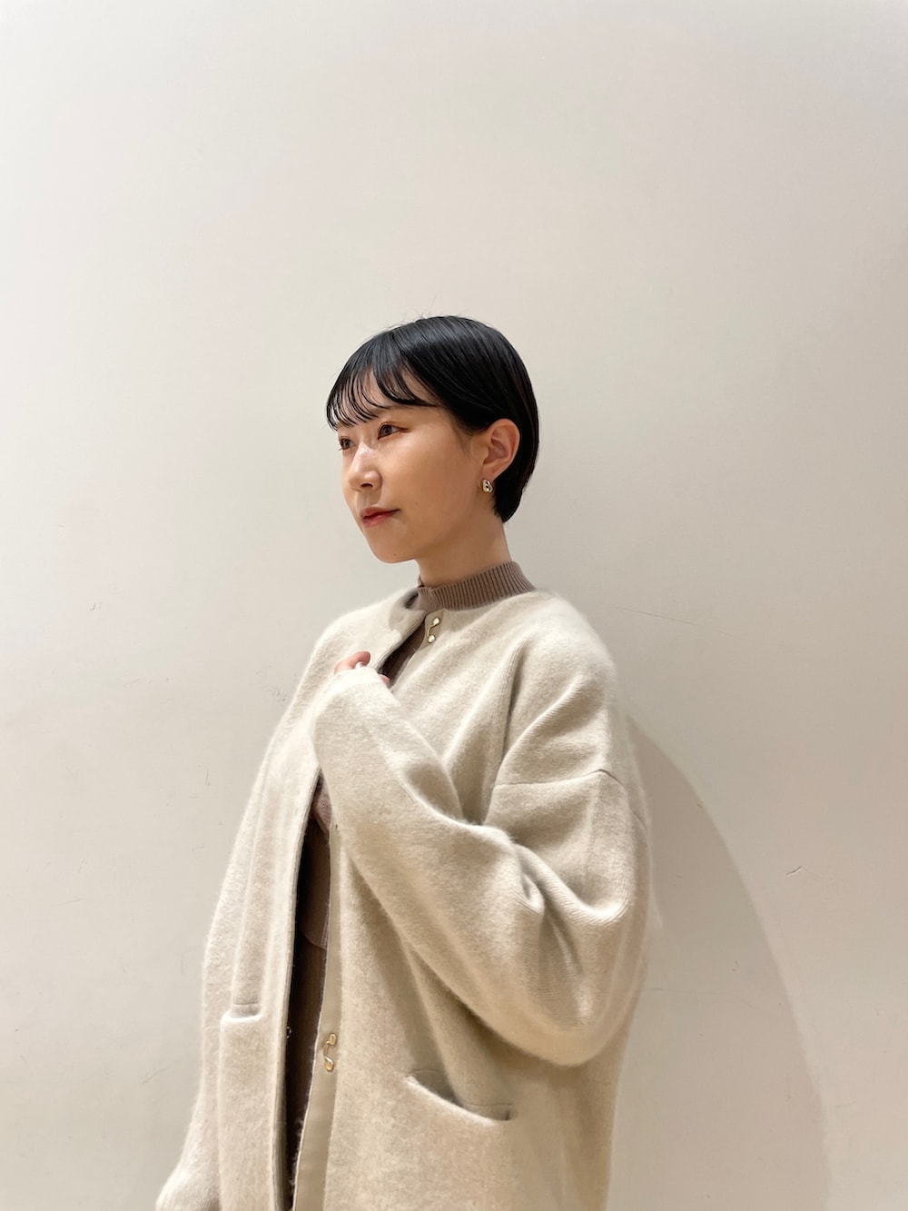 ホワイト系のカーディガン/ボレロ、ベージュ系のワンピース、ホワイト系のハンドバッグを着用したレディースの冬コーディネートの6枚目の写真