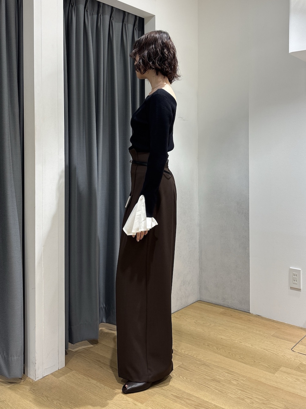 ブラック系のニット/セーター、ブラウン系のその他パンツ、レッド系のハンドバッグを着用したレディースの秋コーディネートの2枚目の写真