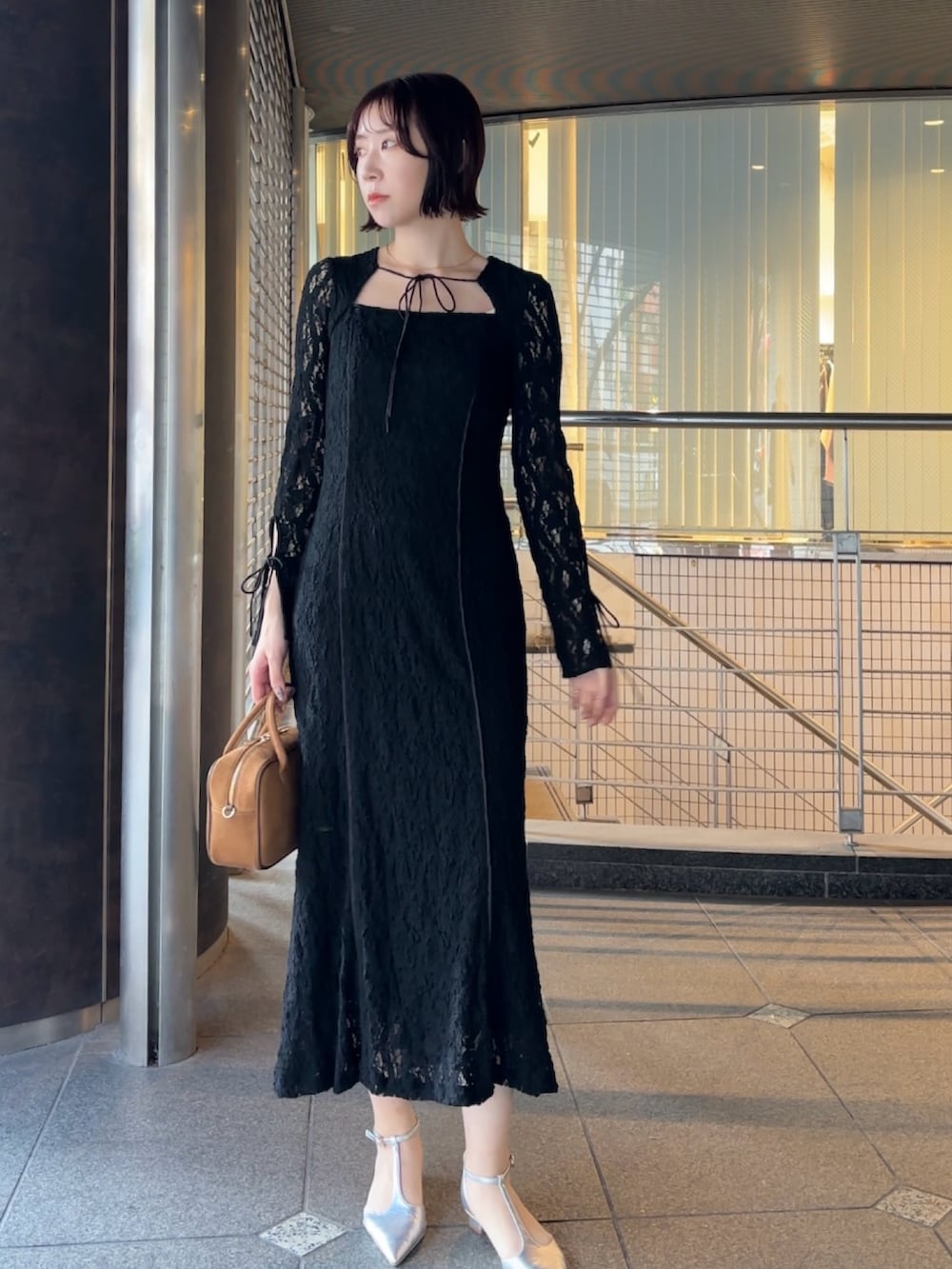 ブラック系のワンピース、イエロー系のハンドバッグ、シルバー系のパンプスを着用したレディースの冬コーディネートの2枚目の写真