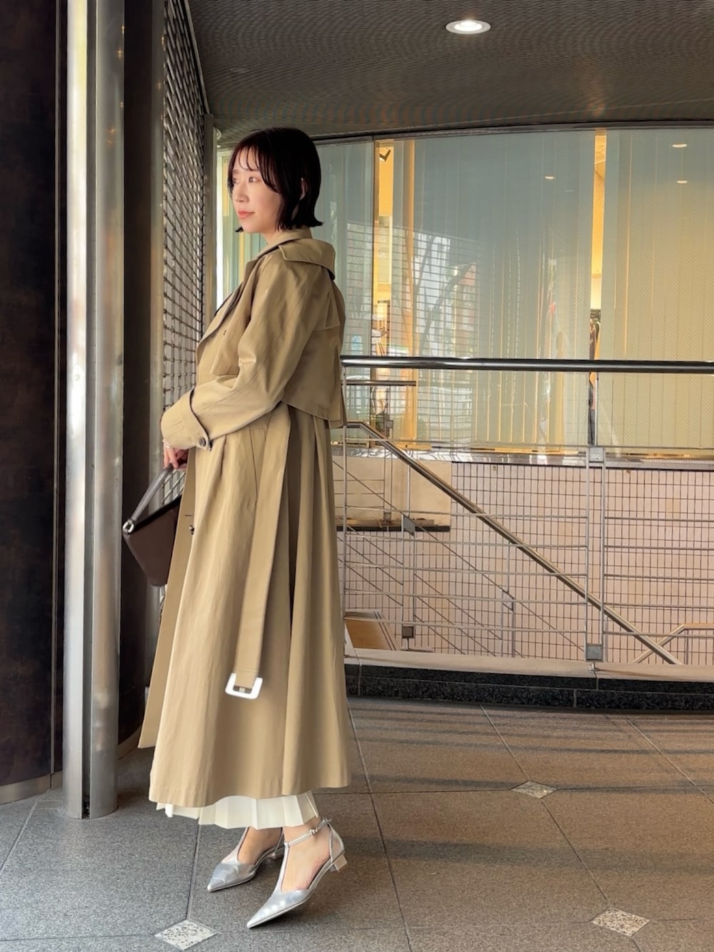 ブラウン系のシャツ/ブラウス、ベージュ系のトレンチコート、ブラウン系のハンドバッグを着用したレディースの冬コーディネートの4枚目の写真