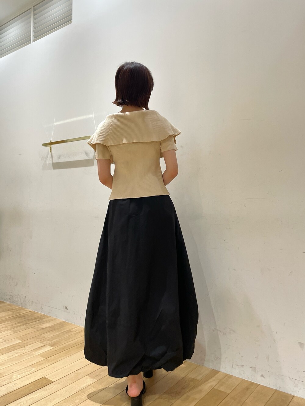 ブラック系のサンダル、ホワイト系のニット/セーター、ブラック系のスカートを着用したレディースの夏コーディネートの6枚目の写真