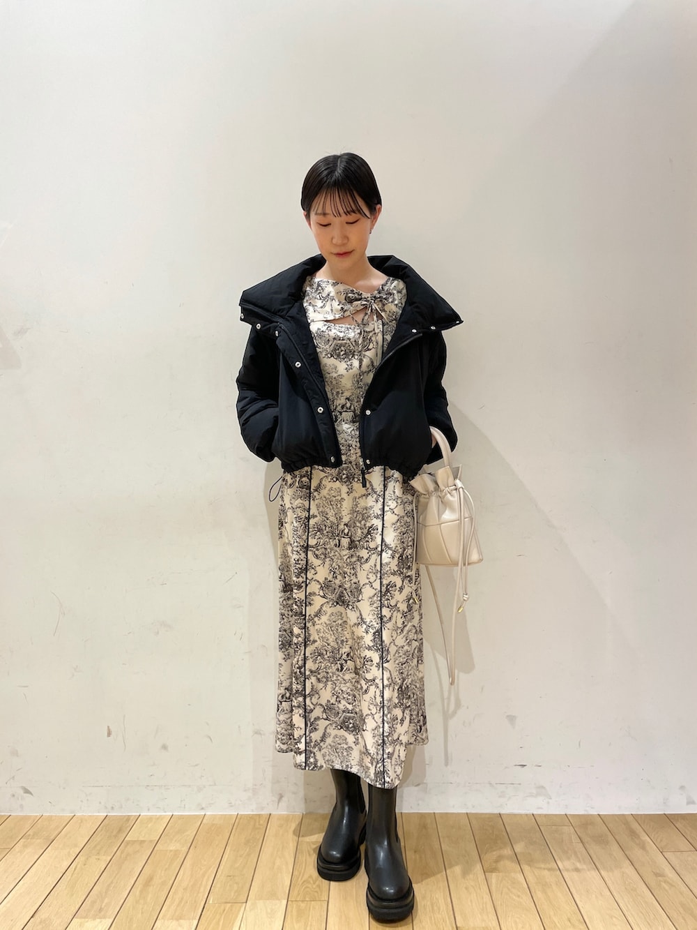 ホワイト系のワンピース、ブラック系のブーツ、ホワイト系のハンドバッグを着用したレディースの冬コーディネートの5枚目の写真