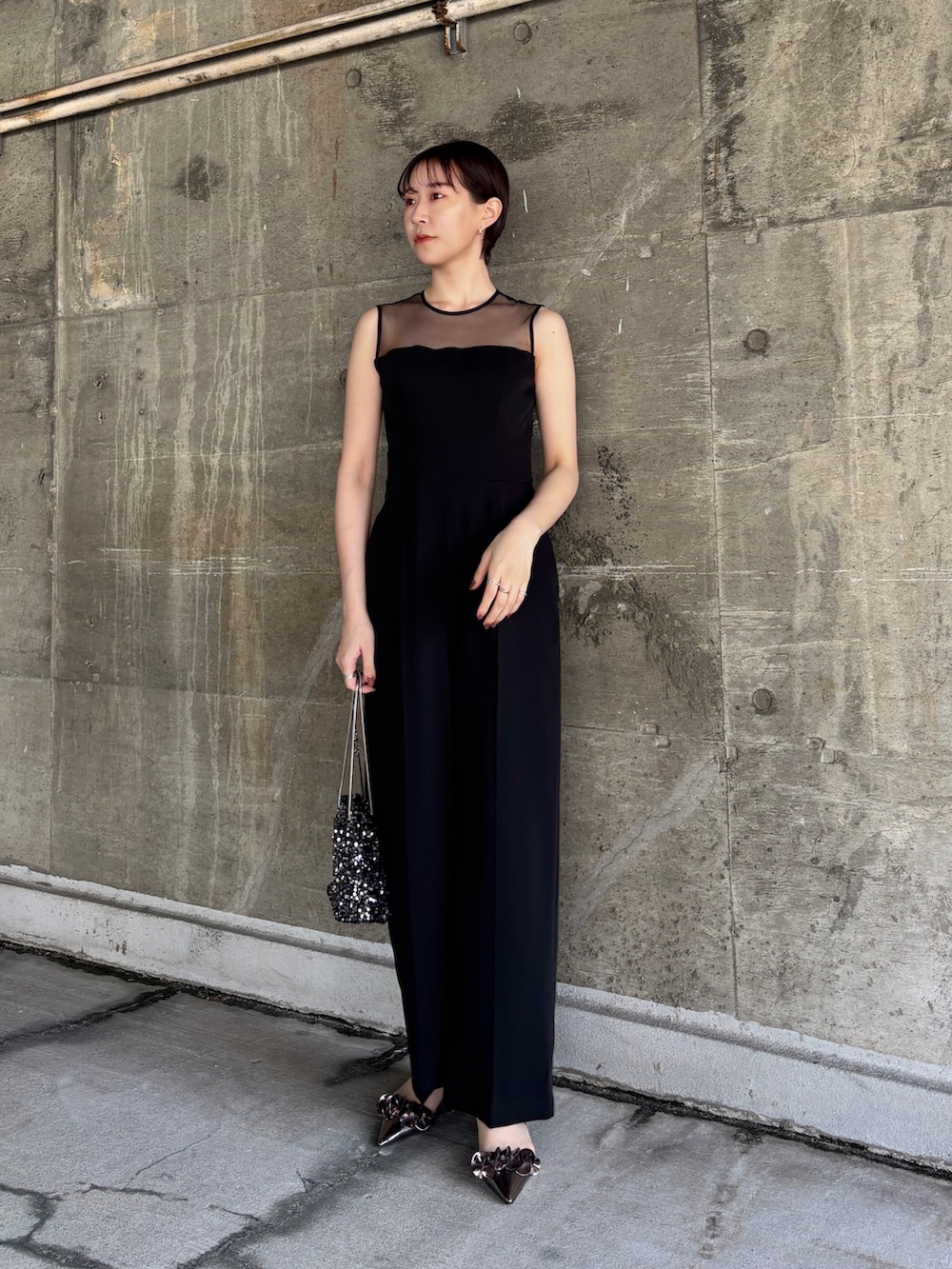 ブラック系のパンツドレス、シルバー系のショルダーバッグ、その他のパンプスを着用したレディースの春コーディネートの3枚目の写真