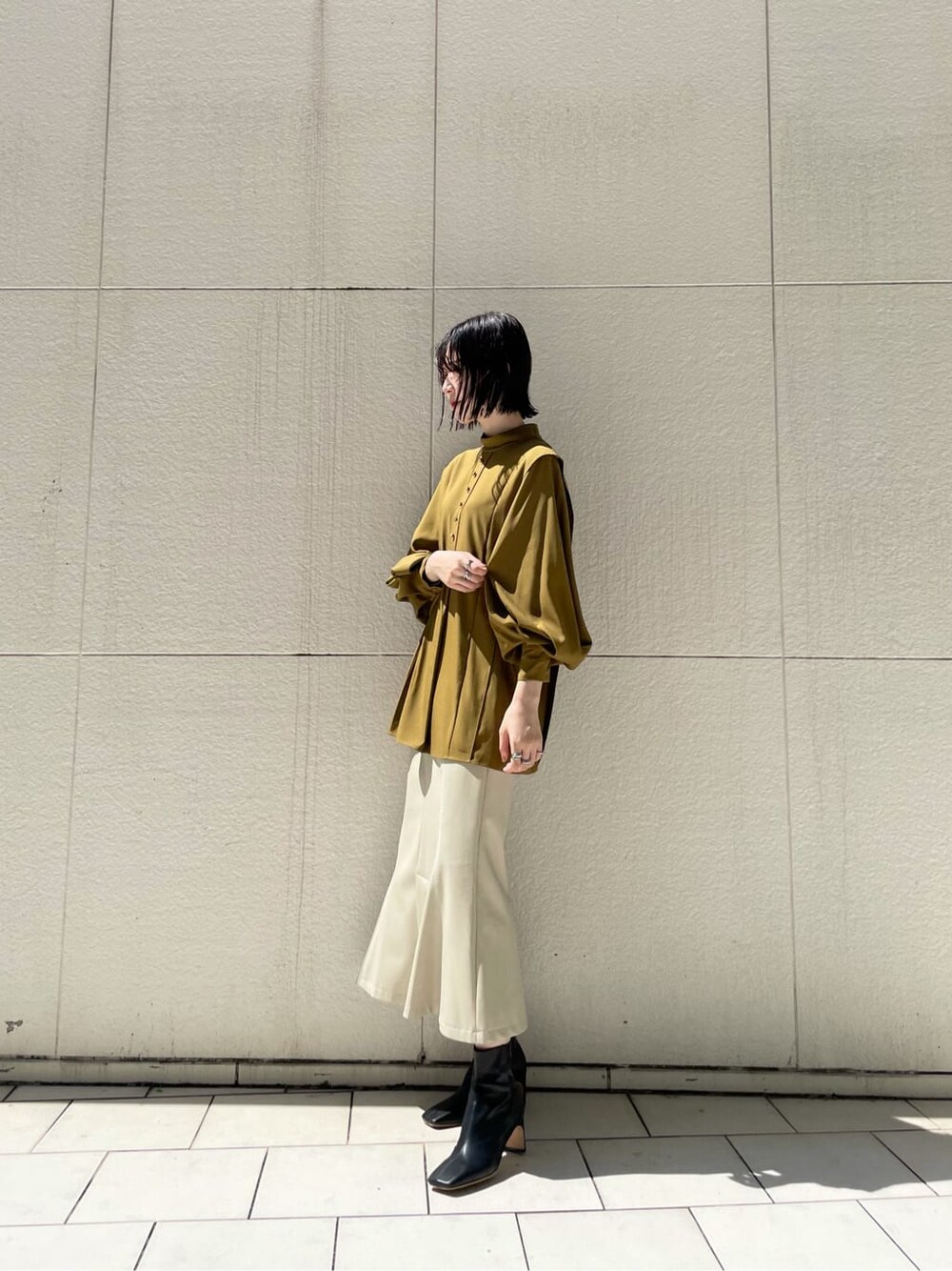 ホワイト系のスカート、ブラック系のその他シューズ、ベージュ系のその他アウターを着用したレディースの秋コーディネートの2枚目の写真