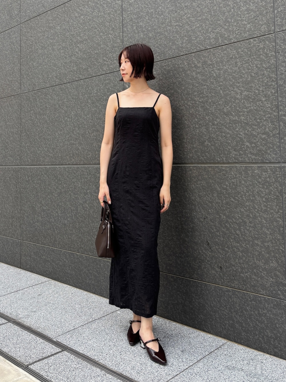 ブラック系のワンピース、ブラウン系のパンプス、ブラウン系のボストンバッグを着用したレディースの夏コーディネートの2枚目の写真
