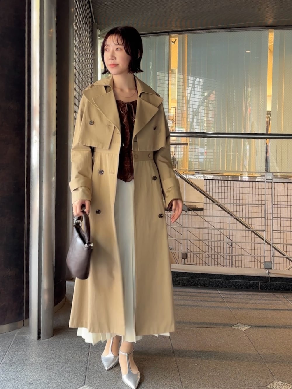 ブラウン系のシャツ/ブラウス、ベージュ系のトレンチコート、ブラウン系のハンドバッグを着用したレディースの冬コーディネートの3枚目の写真