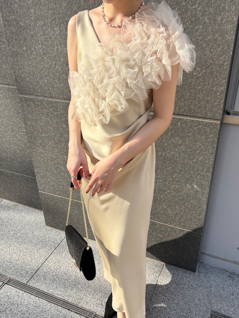 イエロー系のドレス、ブラック系のハンドバッグ、ブラック系のパンプスを着用したレディースの冬コーディネートの4枚目の写真