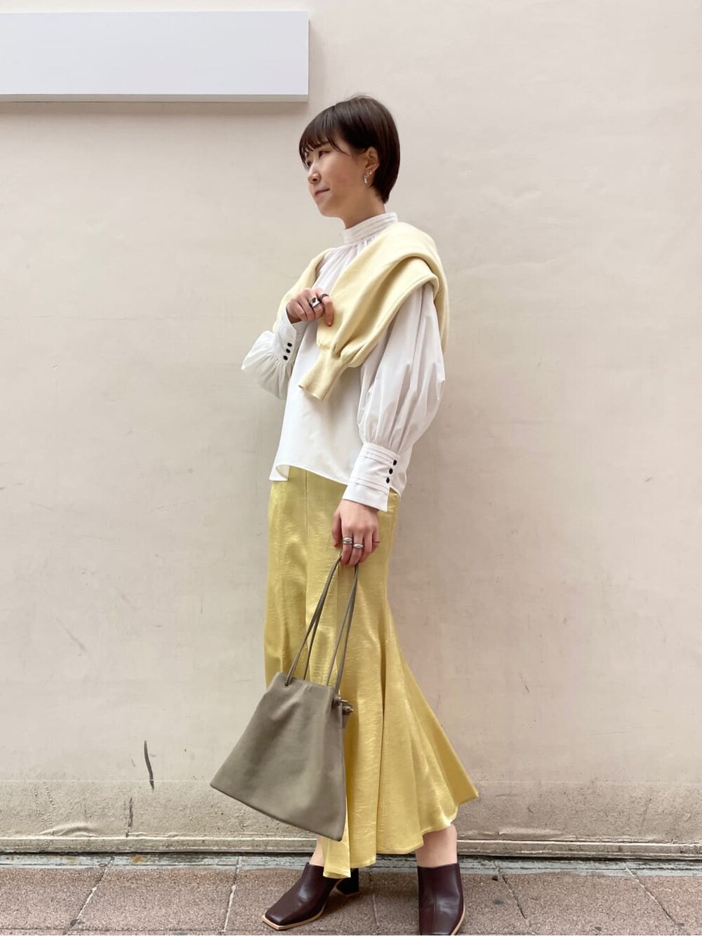 ホワイト系のシャツ/ブラウス、イエロー系のスカート、ベージュ系のハンドバッグを着用したレディースの冬コーディネートの2枚目の写真