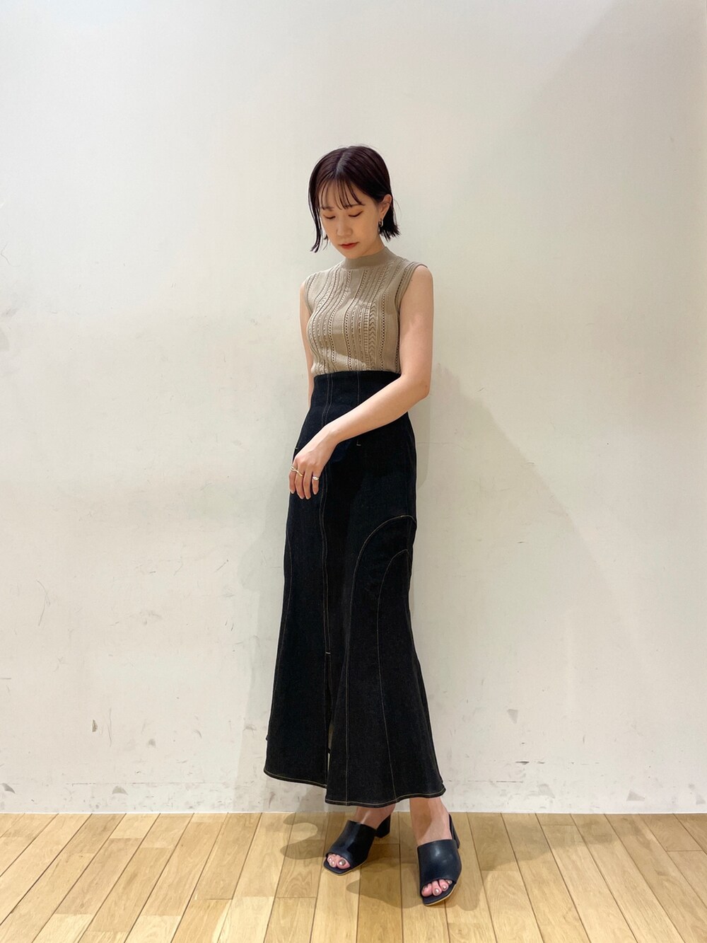 ベージュ系のニット/セーター、ブラック系のデニムスカート、ブルー系のサンダルを着用したレディースの夏コーディネートの2枚目の写真