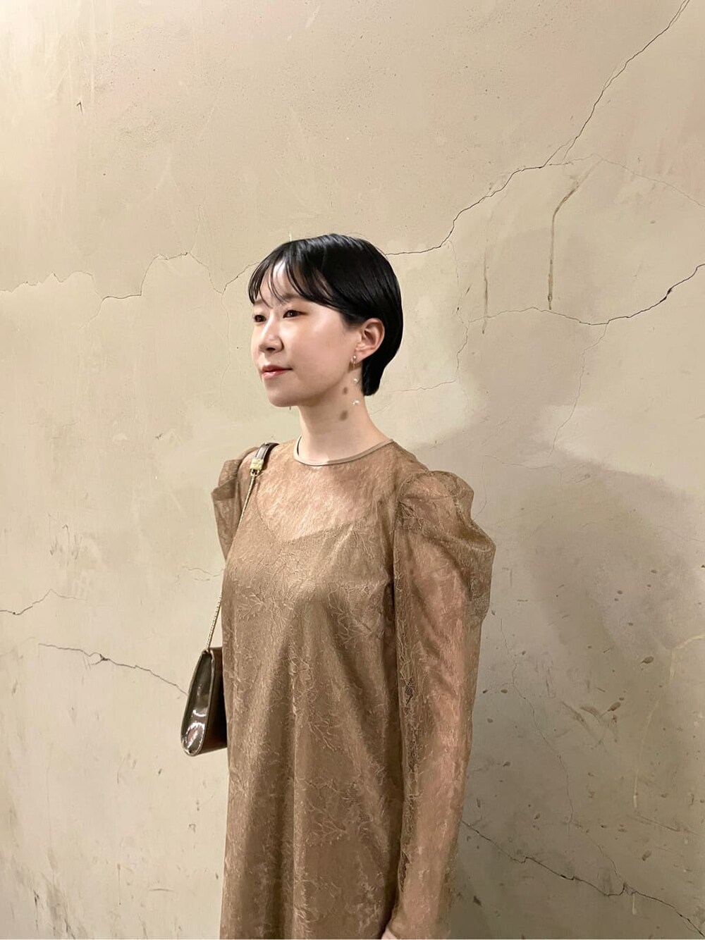 ゴールド系のパンプス、ベージュ系のドレス、ゴールド系のハンドバッグを着用したレディースの秋コーディネートの8枚目の写真