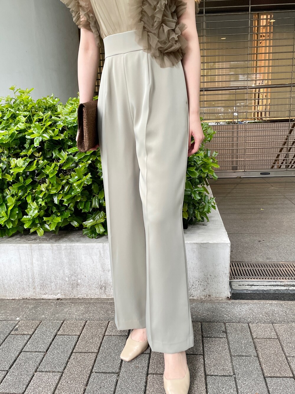 グリーン系のパンツドレス、ベージュ系のパンプスを着用したレディースの春コーディネートの8枚目の写真