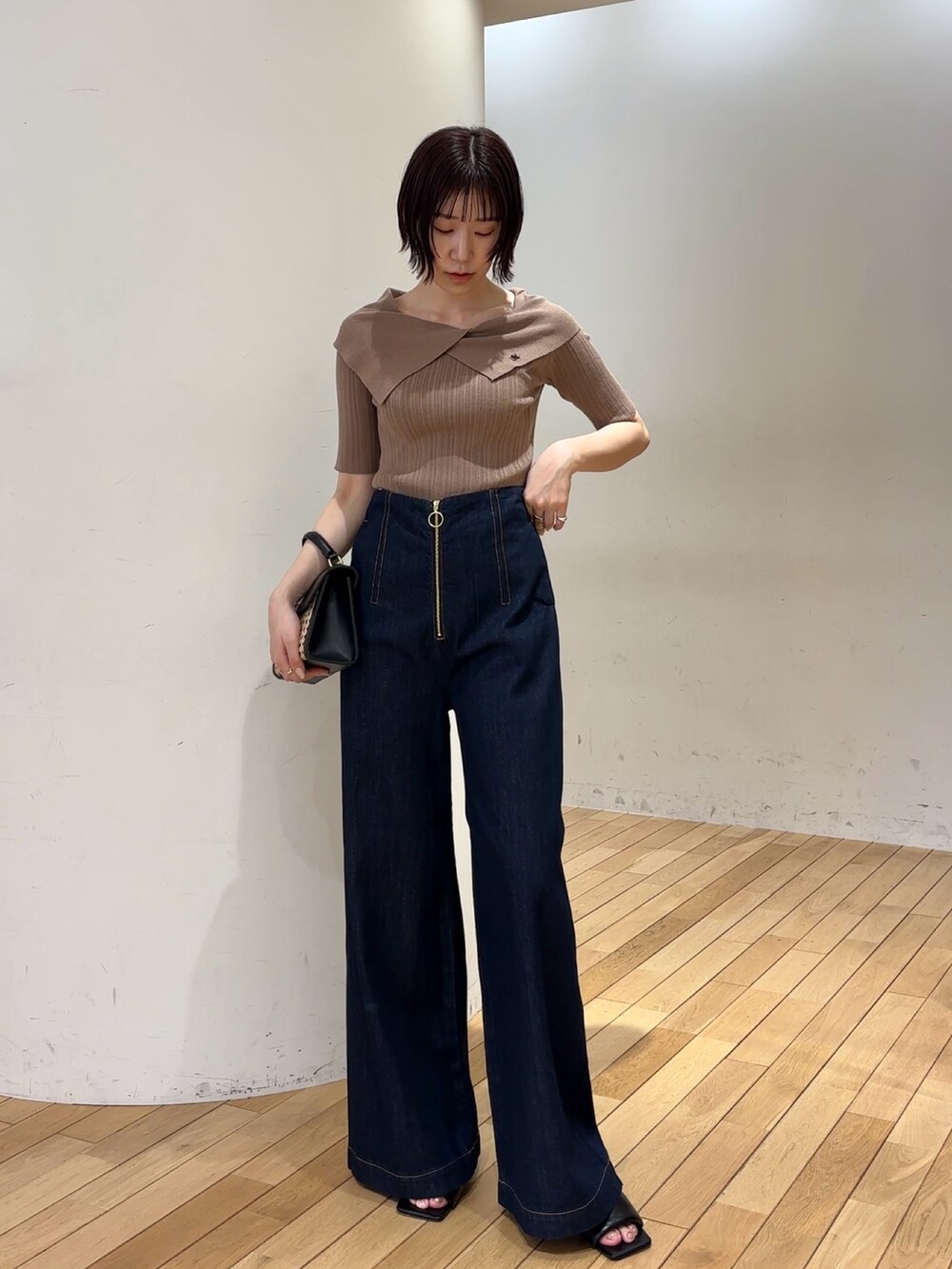 ブラック系のハンドバッグ、ブラック系のサンダル、ブルー系のデニムパンツを着用したレディースの春コーディネートの2枚目の写真