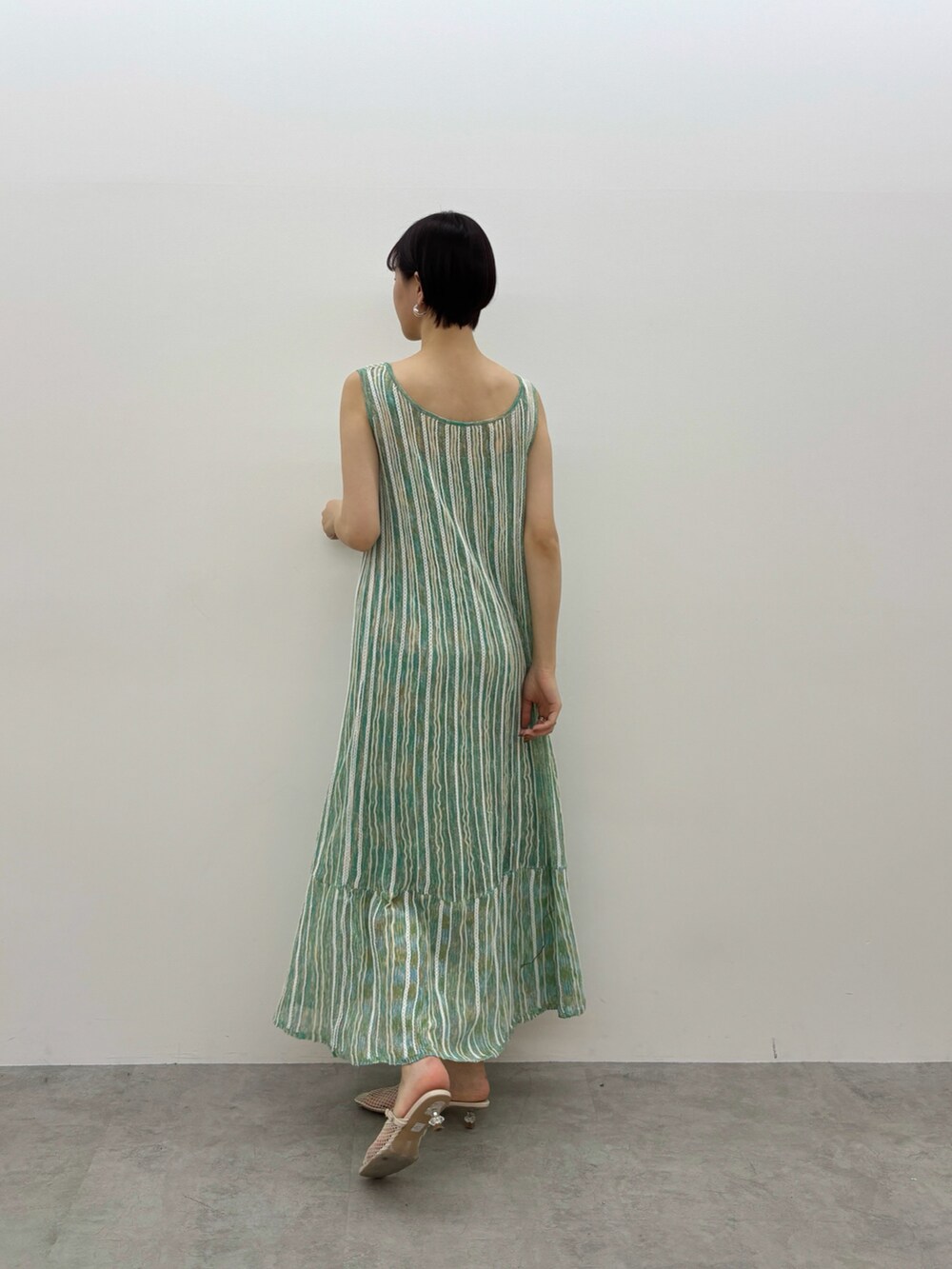 グリーン系のワンピース、ホワイト系のサンダル、シルバー系のピアス（両耳用）を着用したレディースの春コーディネートの3枚目の写真