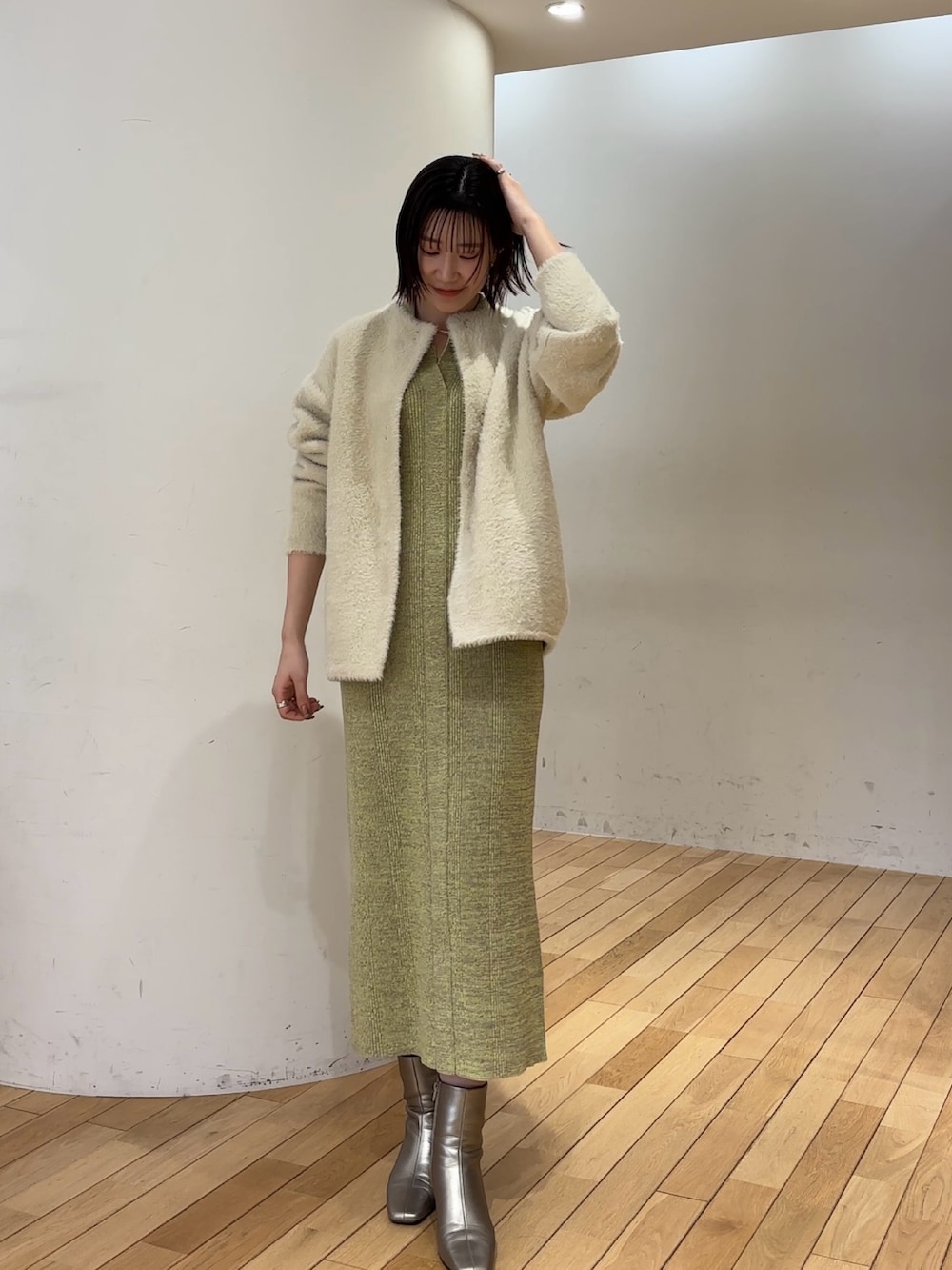 ホワイト系のカーディガン/ボレロ、グリーン系のワンピース、シルバー系のブーツを着用したレディースの冬コーディネートの3枚目の写真